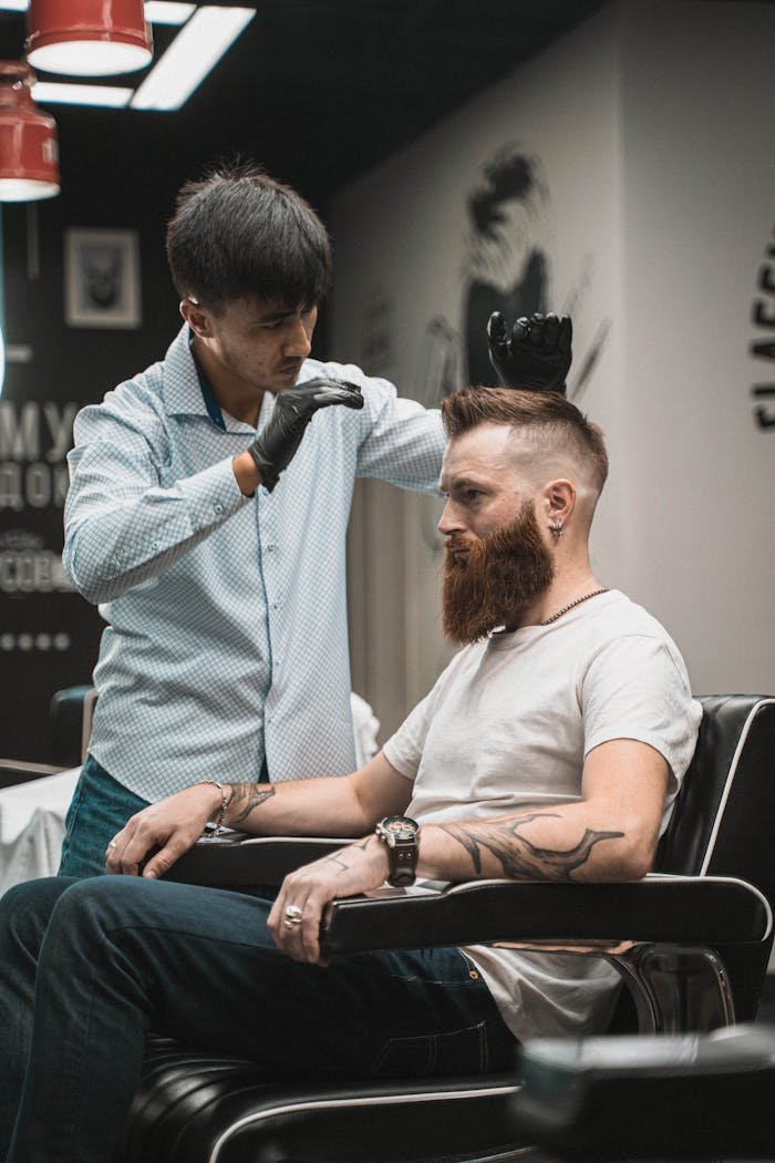 A barber expertly styles a bearded mans hair in a modern barbershop setting.