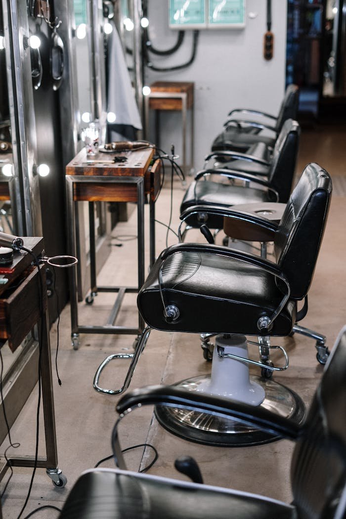 A stylish barber shop interior featuring black leather chairs and mirrors.