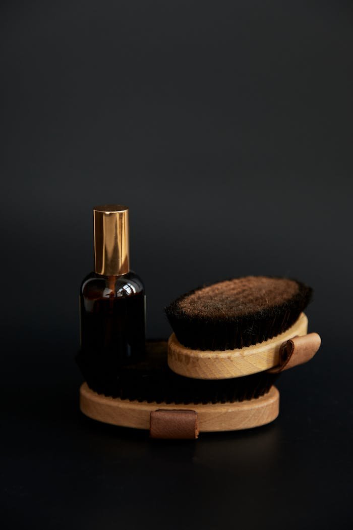 Stylish grooming brushes and elegant bottle against a sleek black background. Perfect for beauty and fashion.